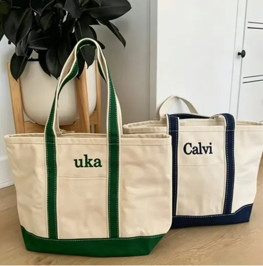 White canvas tote with contrasting black handles, clean lines, placed on marble surface